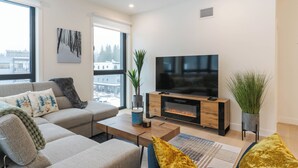 Una sala moderna con un sofá, una mesa de centro, un televisor y una chimenea.