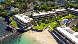 An aerial view of a coastal resort with multiple buildings, a beach, and a clear view of the ocean. - Beachfront 2BR Townhouse w/ Ocean Sunset Views (Lahaina)