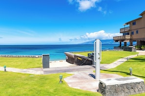 A coastal hotel with a stone pathway leading to a grassy area and a view of the ocean.