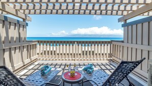 A balcony with two lounge chairs, a small table with a bottle and glasses, and a view of the ocean. - Beachfront 2BR Townhouse w/ Ocean Sunset Views (Lahaina)