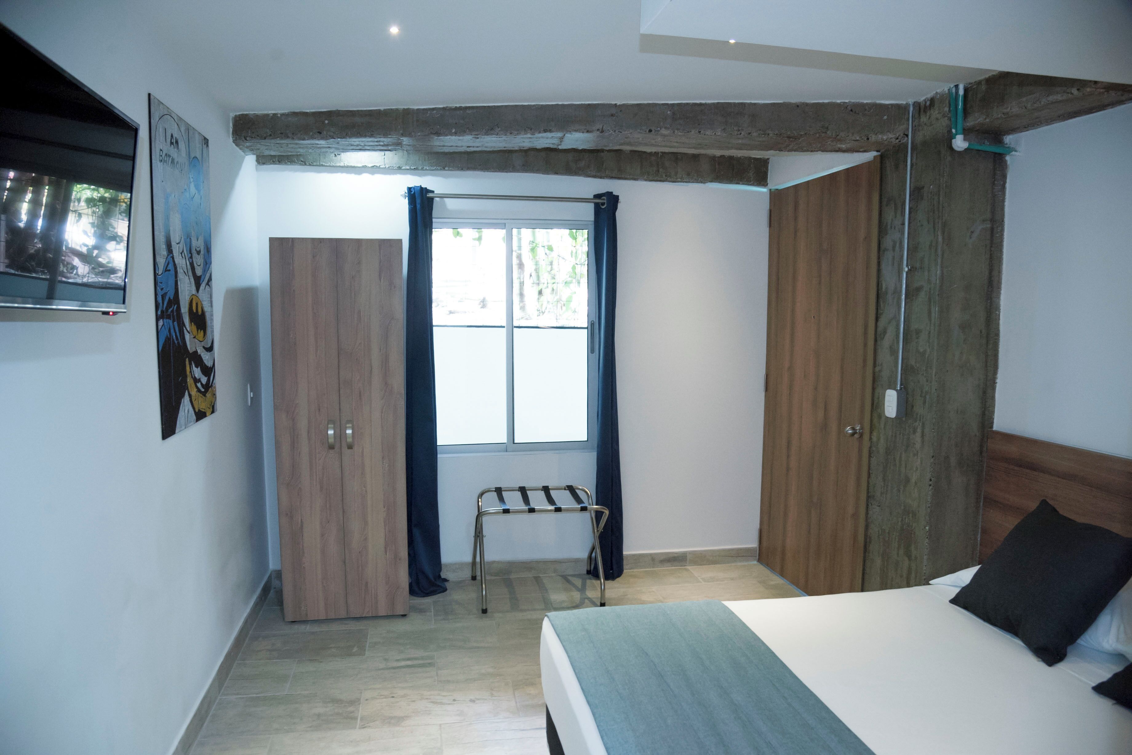 Un dormitorio con cama, armario de madera y ventana con cortinas.