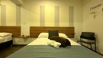 A hotel room with a large bed, a wooden headboard, a nightstand, a chair, and a wall with a motivational quote.