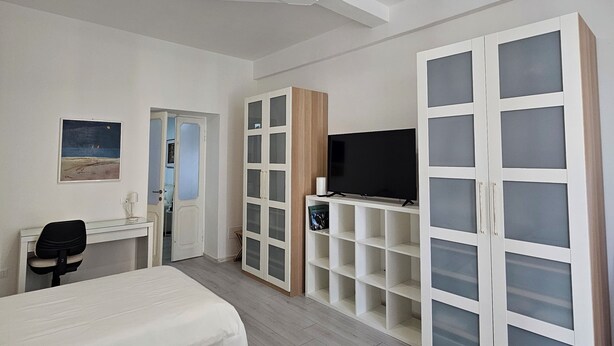 Une chambre moderne avec deux lits, un bureau, une télévision et une armoire aux portes en verre.