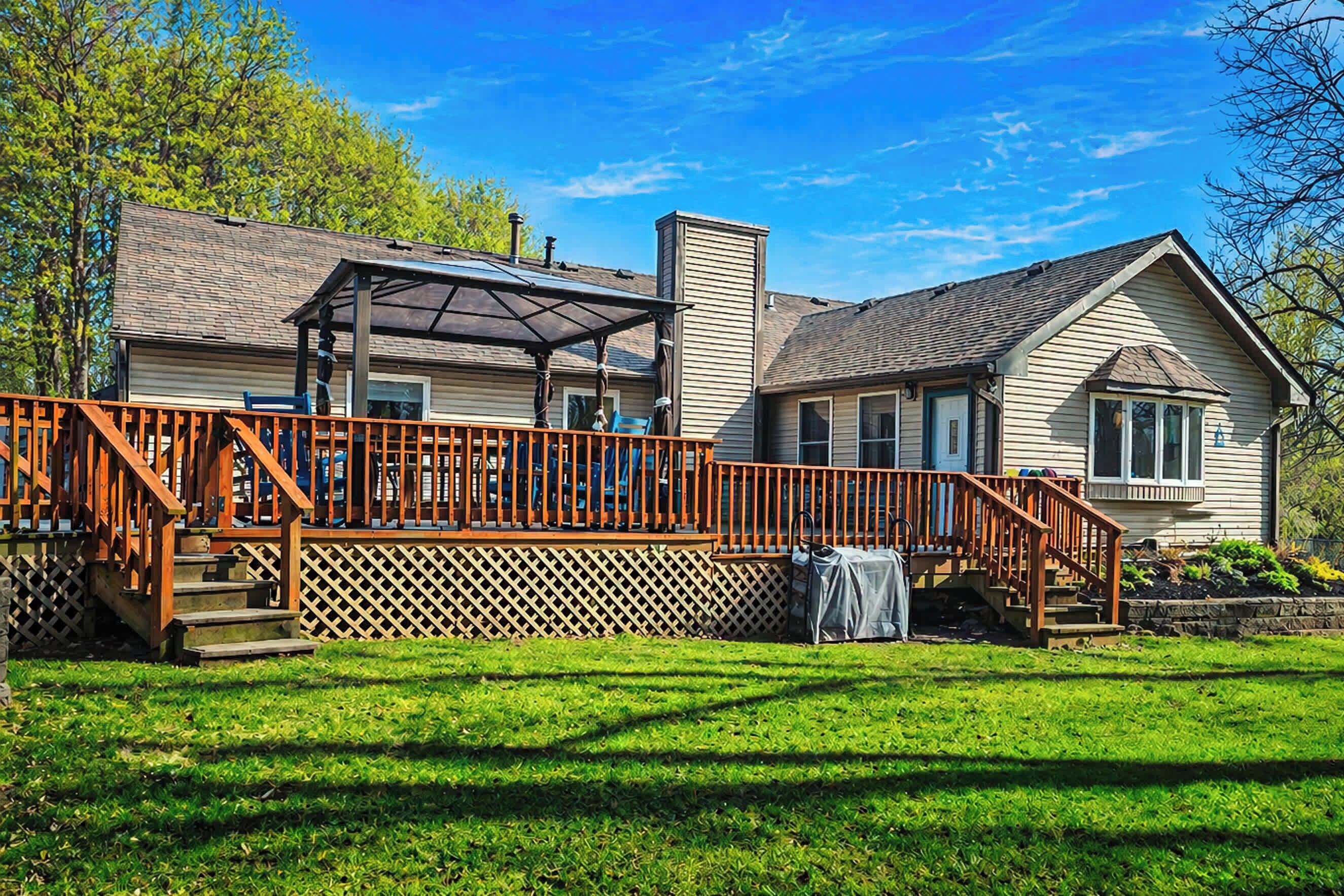 A house with a wooden deck, a covered patio, and a fenced yard.