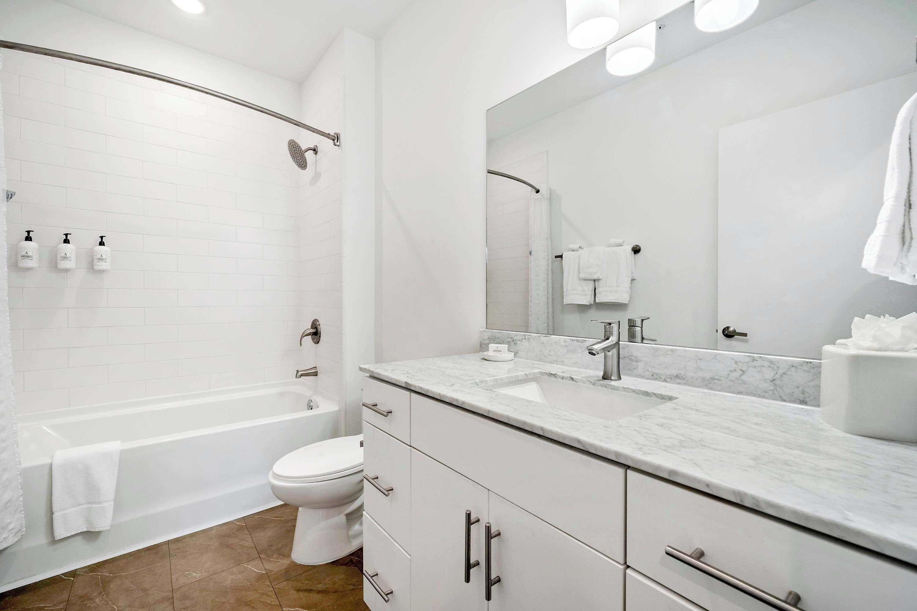 Une salle de bain moderne équipée d’une baignoire, de toilettes et d’un meuble-lavabo avec un évier et un miroir.