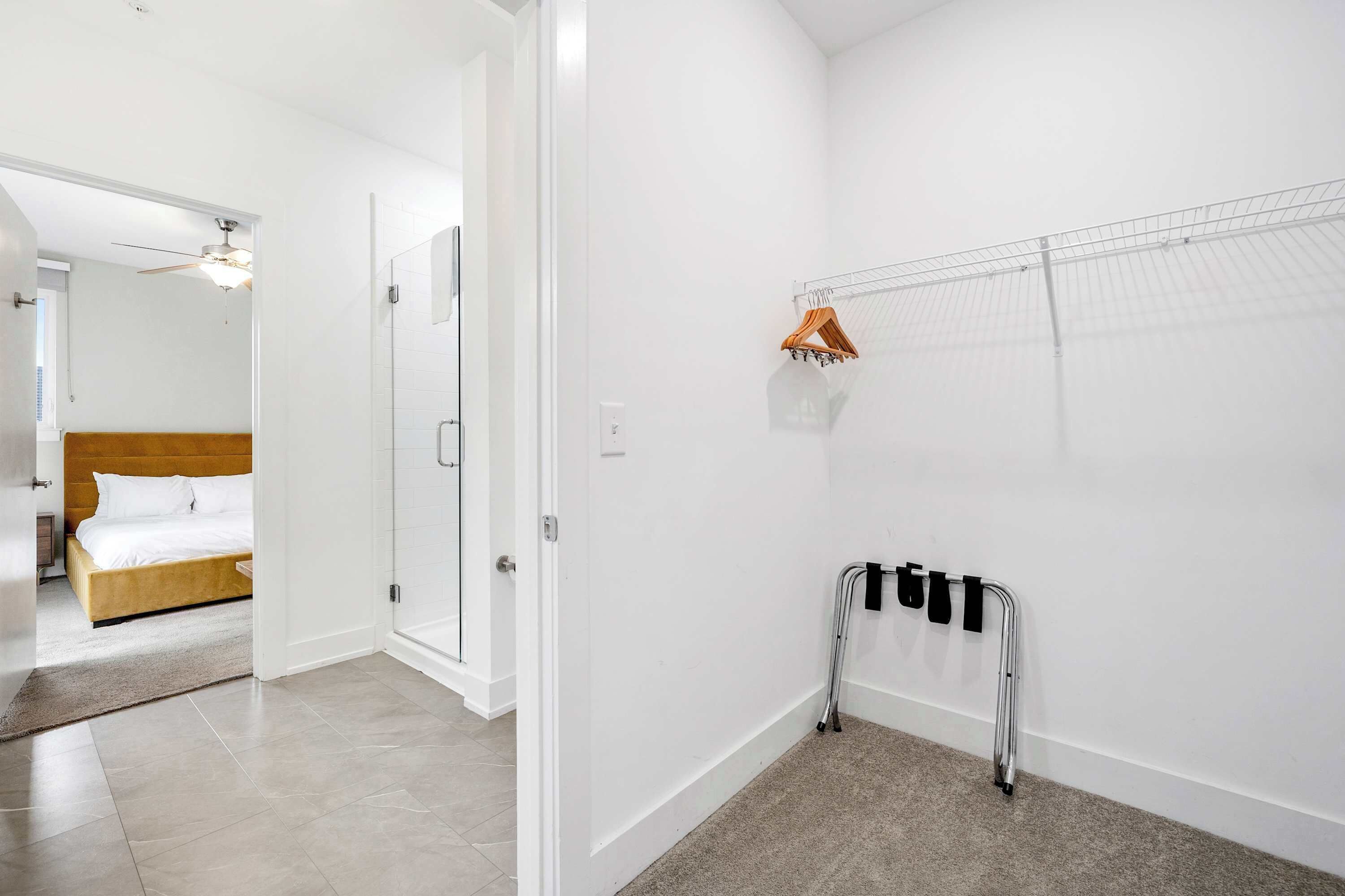 A hotel room with a bed, a shower area, and a handrail against the wall.
