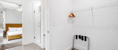 A hotel room with a bed, a shower area, and a handrail against the wall.