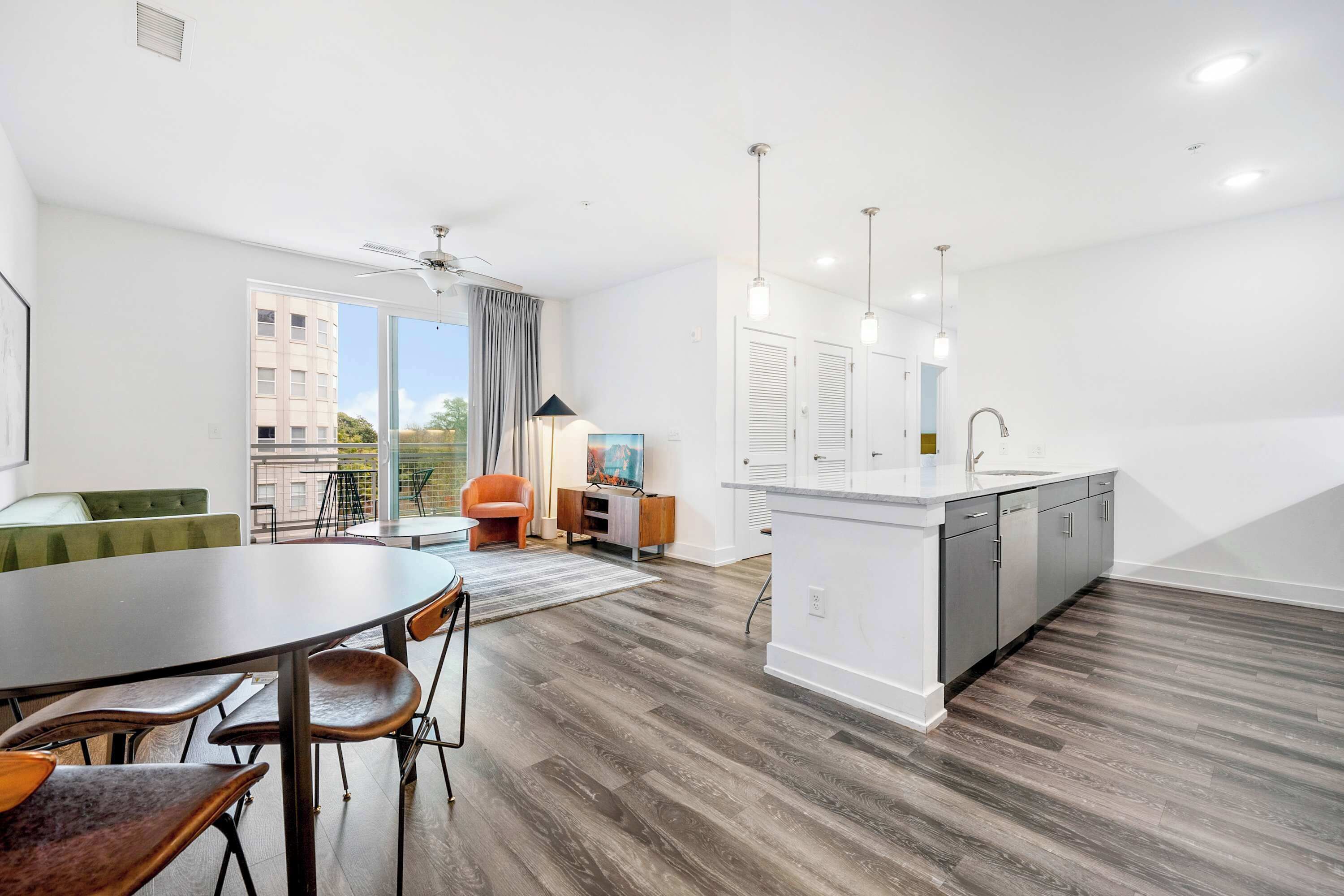 Un appartement moderne comprenant un coin repas, une cuisine et un balcon avec vue sur la ville.