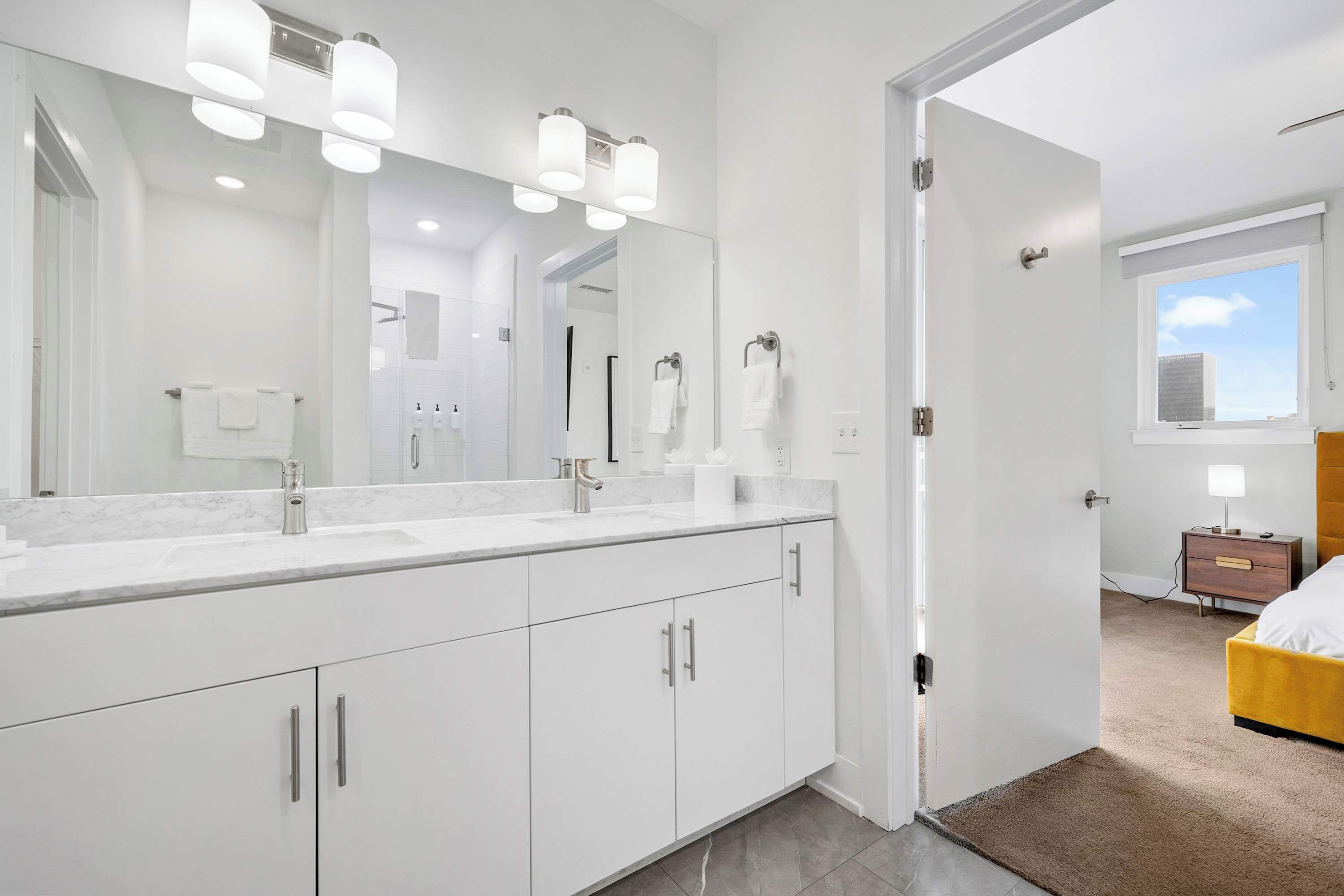 A modern bathroom with a large mirror, white cabinetry, and a vanity with a sink.