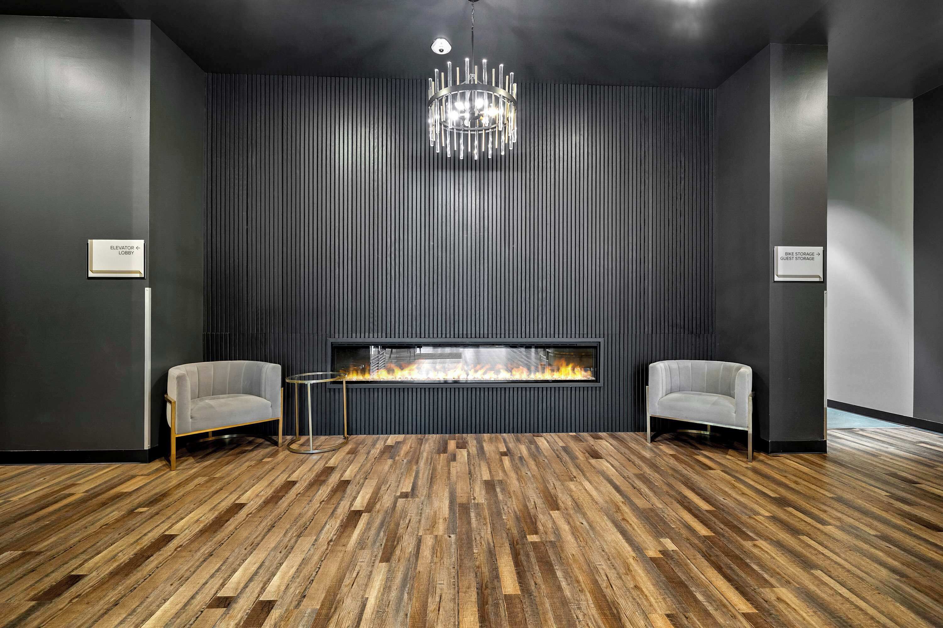 Una habitación moderna con chimenea, dos sillones y suelo de madera.