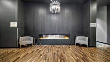 Una habitación moderna con chimenea, dos sillones y suelo de madera.