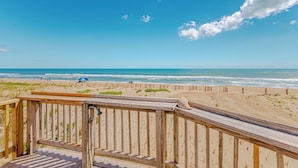Een houten terras met uitzicht op het strand en de zee.