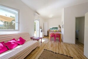 A modern living room with a sofa, a small table, and a kitchen area in the background. - Oasis - Apulian Villa WaCa (Puglia)