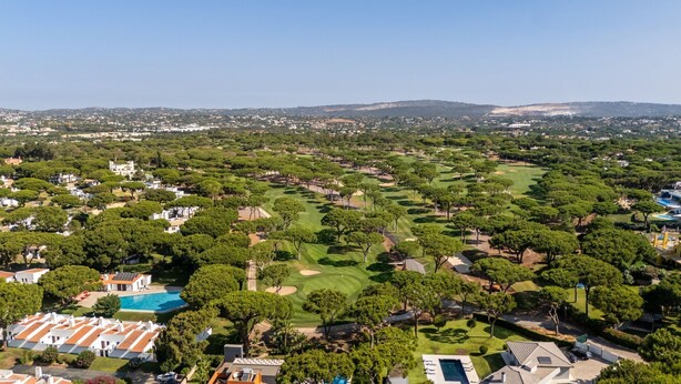 Campo de golf con piscina y edificios residenciales en primer plano.