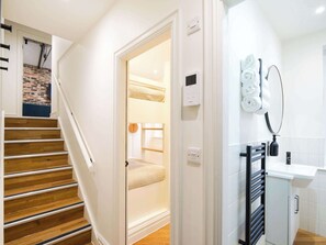 A staircase leading to a room with a bed, a thermostat, and a towel rack in a modern interior. - Serge | The Heim (Greater Manchester)