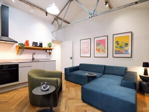 A modern living space with a kitchen, a sofa, a small table, and artwork on the wall. - Serge | The Heim (Greater Manchester)