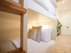 Ein Hotelzimmer mit Bett, Kissen, einem Holzbalken, einer Topfpflanze und einer Tür.