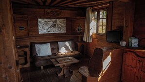 Ein gemütliches Blockhauss-Interieur mit einer Holzcouch, einem kleinen Tisch und einem Fernseher.