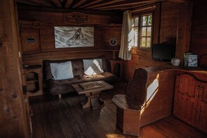 Ein gemütliches Blockhauss-Interieur mit einer Holzcouch, einem kleinen Tisch und einem Fernseher.
