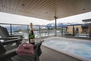 A rooftop terrace with a hot tub, seating area, and a bottle of champagne. - Max Send (Revelstoke)