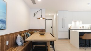 Cozinha moderna com um banco de madeira, uma mesa de jantar e uma luminária pendente.