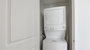 Ett litet, vitt tvättrum med en tvättmaskin med frontmatning och en torktumlare.