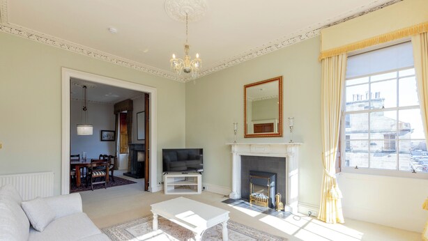 A living room with a sofa, a white coffee table, a fireplace, and a television. - Spacious, central, top floor, period apartment w/park views (Edinburgh)
