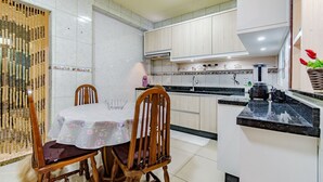 A kitchen with wooden cabinets, a marble countertop, and a dining area with a table and chairs. - Casa com Ar e Wi-fi pr Xima Praia da Tapera (Florianópolis)