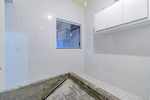 A bathroom with white tiled walls, a window, and a shower area. - Casa com Ar e Wi-fi pr Xima Praia da Tapera (Florianópolis)
