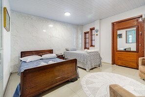 A bedroom with two beds, a wooden door, and a white floor. - Casa com Ar e Wi-fi pr Xima Praia da Tapera (Florianópolis)