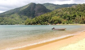 A beach with a boat on the water and mountains in the background. - Casa com Ar e Wi-fi pr Xima Praia da Tapera (Florianópolis)