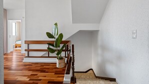 A staircase with a wooden handrail, a potted plant, and a bench. - John's Villa by Homie (Canhas)