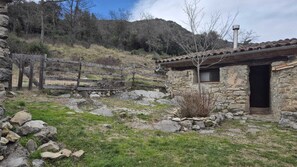 A rustic stone building with a tiled roof, a wooden fence, and a rocky landscape. - Real disconnection in Alta Garrotxa. Nature, calm and home cooking. (Oix)