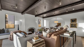 Een moderne woonkamer met een open haard, een zithoek, een eettafel en een kroonluchter.