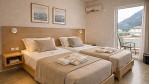 Habitación de hotel con dos camas, un escritorio pequeño, una silla y un balcón con vistas a la montaña.