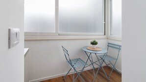 A corner room with a window, a small table with a plant, and two blue chairs. - Room 2 - Anita Rooms Bari (Bari)