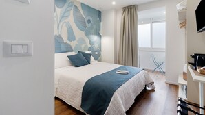 A bedroom with a bed, a wall-mounted power outlet, a window with curtains, a desk with a kettle, and a chair. - Room 2 - Anita Rooms Bari (Bari)