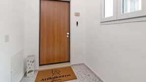 A wooden door with a doorknob, a small electronic device on the wall, and a doormat with a logo. - Room 3 - Anita Rooms Bari (Bari)