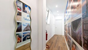 A hallway with a wall-mounted collage of photos, a fire extinguisher, and a wooden floor. - Room 3 - Anita Rooms Bari (Bari)