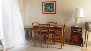 A dining area with a wooden table and chairs, a small side table with a lamp, and a framed painting on the wall. - Oceanfront retreat in with AC and pool (Inch Marlow)