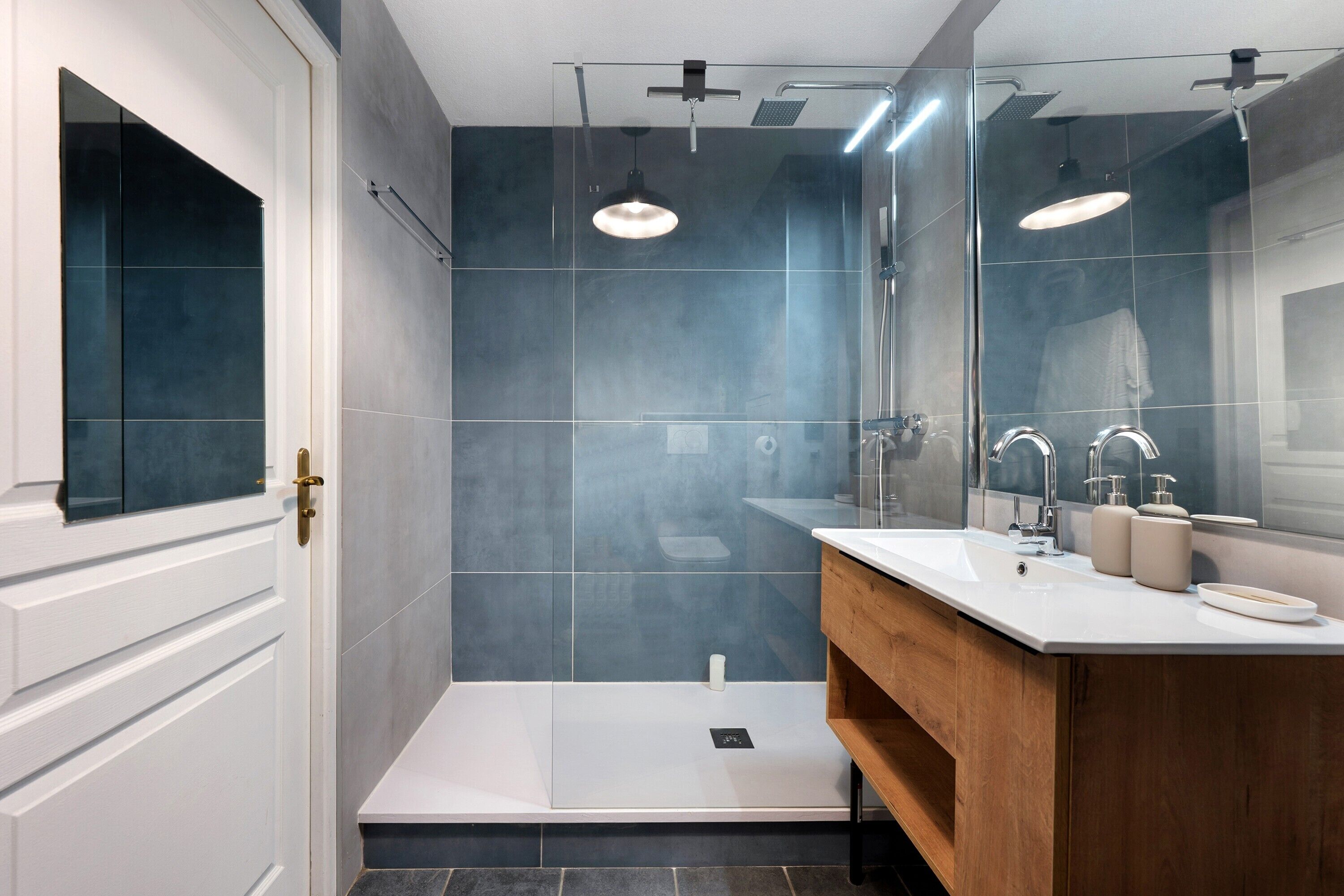 A modern bathroom with a shower, a vanity with a mirror, and a toilet.