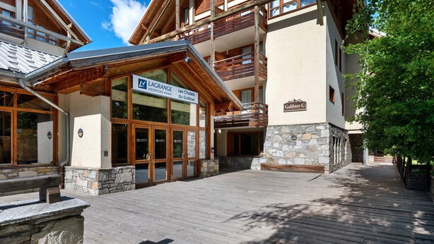 A hotel entrance with a sign for 'LAGRANGE Les Chalets du Galibier' and a wooden deck leading to the building.