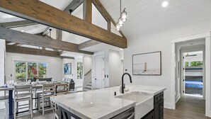 Un'ampia cucina con un'isola grande, travi in legno e un'area pranzo con sedie e tavolo.