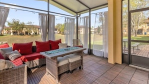A covered outdoor seating area with wicker furniture and a table, overlooking a residential neighborhood. - Headline (Davenport)