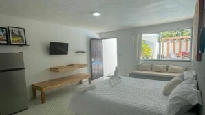 Ein Schlafzimmer mit Bett, einer Bank, einem Fernseher und einem Fenster mit Blick ins Freie.