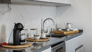 A modern kitchen with a sleek black countertop, a built-in oven, and a stainless steel sink. - John s Villa by Homie (Ponta do Sol)