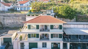 A two-story building with a red-tiled roof, green shutters, and a balcony on the upper floor. - John s Villa by Homie (Ponta do Sol)
