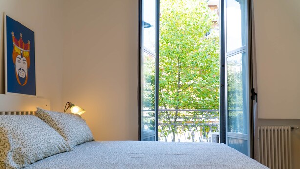 A bedroom with a bed, a window, and a painting on the wall. - BIG Design Portello Milano (Milano)