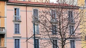 A multi-story building with balconies, a storefront, and parked cars. - BIG Design Portello Milano (Milano)