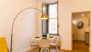 A dining area with a round table, two chairs, a floor lamp, and a window with blinds. - BIG Design Portello Milano (Milano)